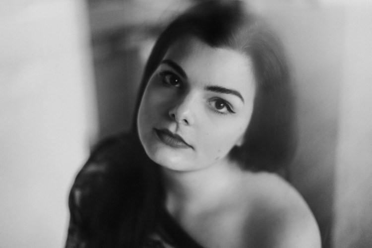 Mynda af ungri dökkhærðri stúlku sem hallar undir flatt og horfir beint í myndavélina.